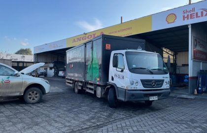 Camión de transporte industrial de Solitrans detenido frente a un taller automotriz, listo para operación de retiro de residuos.