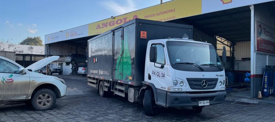 Camión de transporte industrial de Solitrans detenido frente a un taller automotriz, listo para operación de retiro de residuos.
