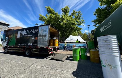 Camión de Solitrans realizando operación de recolección de residuos en una campaña de reciclaje al aire libre, con tambores industriales y personal trabajando.